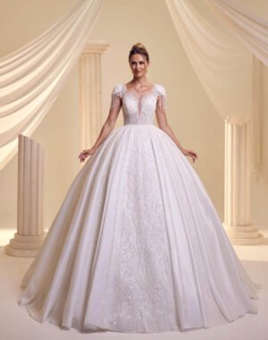 Kapkollu Kesimiyle Göz Alıcı Bu Gelinlik, V Yaka Formu, Omuzlardan Dökülen İnce Püskül İşlemeleri Ve Yoğun Işıltılı Etek Deseniyle Göz Alıcı Bir Prenses Model Gelinlik